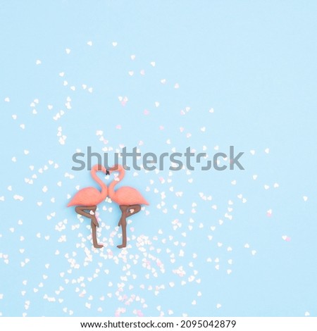 Trendy love composition with two pink flamingos forming a heart on blue pastel background. Valentine's day concept