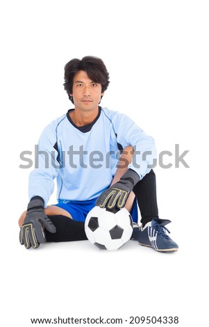 Goalkeeper in blue holding ball on white background