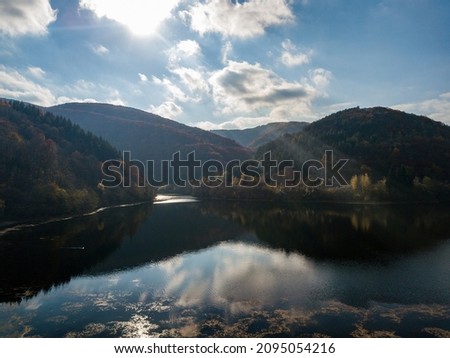 An Aerial shot of a small lake in the middle of cliffs and autumn view of colorful trees