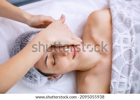 Face and head massage for a young woman. Alternative health methods with aromatic oils. Cosmetology procedures for face and body skin. Skin care in adulthood. Horizontal photo.