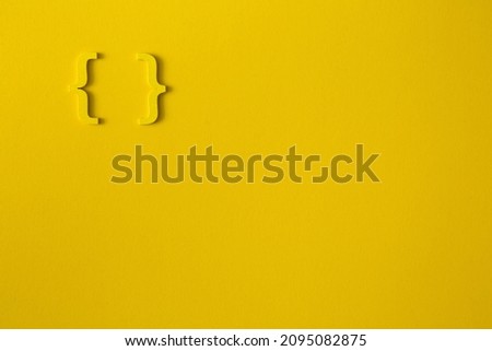 Yellow wooden symbol "bracket" on yellow background and copy space for social media educational concept Royalty-Free Stock Photo #2095082875