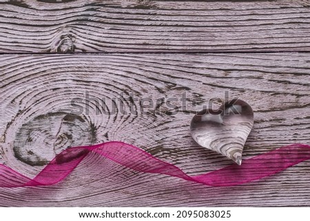 Bright ribbon and transparent glass heart on a wooden background. The concept of Valentine's Day. Flat lay.