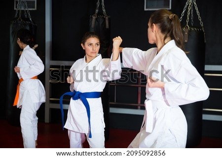 Portrait of concentrated woman wearing white kimono sparring with female opponent during martial arts training