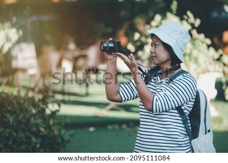 Travel concept, Asian woman tourists with relaxing on city streets, Portrait asian female backpacker wearing hat traveling take digital camera retro picture style, Happy relaxing on holiday.