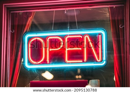A bright neon open sign hanging in a shop window