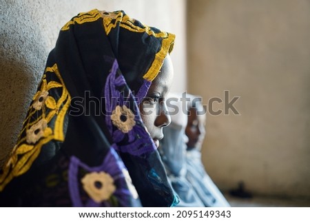 Side view of a veiled black african girl waiting for her wedding ceremony; child marriage concept Royalty-Free Stock Photo #2095149343