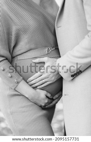 A Grayscale closeup shot of a pregnant woman with a man hugging