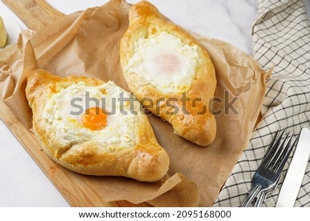 Traditional georgian dish of cheese-filled bread adjarian khachapuri with fried egg on a wooden board