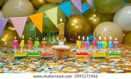 Happy birthday for 1 year old baby greeting card, festive cupcake with burning candles and birthday decorations on a blue background