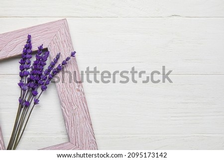 Beautiful lavender flowers and empty picture frame on light wooden background