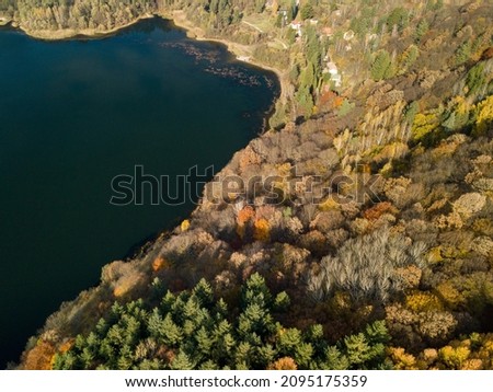 An Aerial shot of a small lake in the middle of cliffs and autumn view of colorful trees