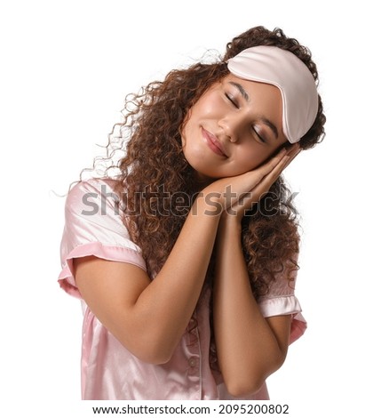 Young African-American woman with pink sleeping mask on white background