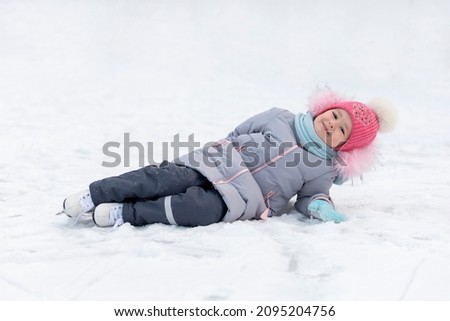 little girl learning ice skating in park on rink. children winter sport. outdoor games, pastime wintertime. kids with skates on cold freezing day. Snow outdoor fun for child. Christmas family vacation
