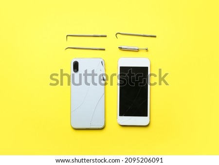 Broken mobile phones and technician tools on yellow background