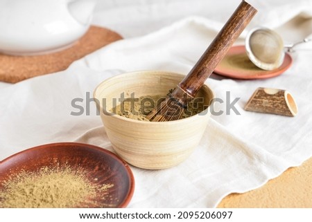 Bowl with powdered matcha tea and chasen on table