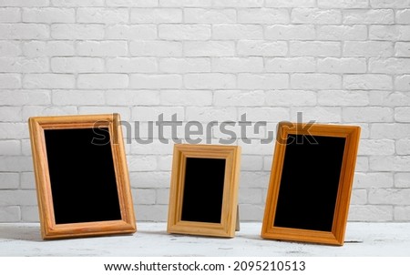 old photo frames on the wooden table, white brick wall