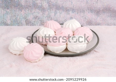 Russian dessert zefir or zephyr on gray plate on pink fur background. Marshmallow closeup picture.
