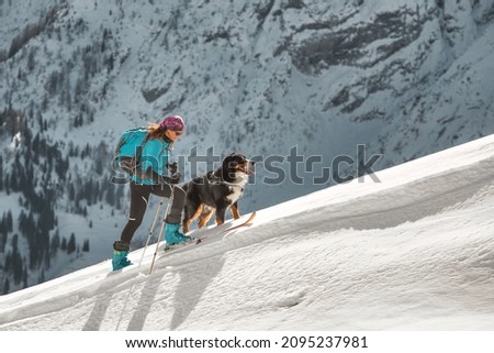 Ski mountaineering climb on a ridge a girl with her dog