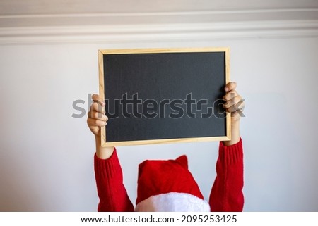 Christmas without waste. Toddler boy in pajamas sits on bed and holds black tablet for text in his hands. Concept of preparing for the holiday at home.