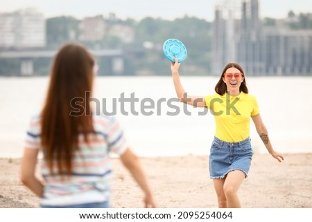 Beautiful young women playing frisbee near river