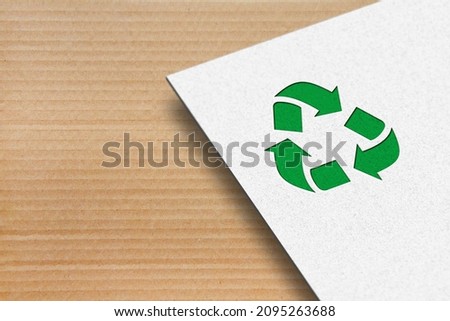 Recycle symbol with white paper on a cardboard background