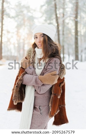 smiling and joyful woman walking and enjoying the winter forest on a sunny frosty day. Camping and outdoor walks outside the city in the park