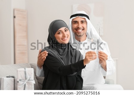 Young Muslim couple with sparklers at home Royalty-Free Stock Photo #2095275016