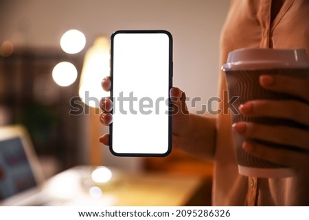 Woman holding modern mobile phone and paper cup of coffee, closeup