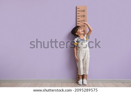 Little boy measuring height near color wall Royalty-Free Stock Photo #2095289575
