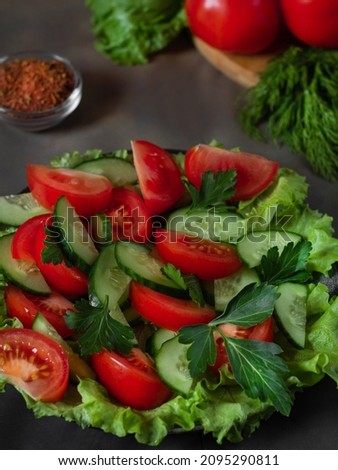 Salad. Dish with salad close-up. Tomatoes, cucumbers, lettuce. In the background there are tomatoes and spices. Photo on a beige background. Selective focus.