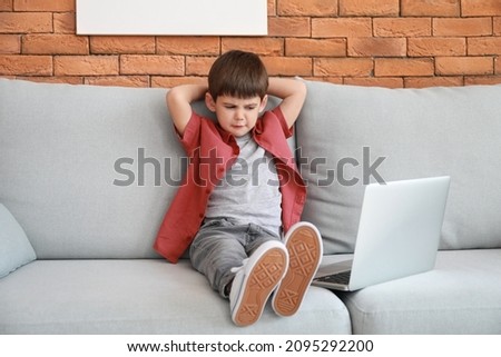 Little boy watching cartoons with laptop on sofa at home