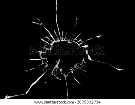 Texture of cracks on the window, broken glass with a hole on a black background