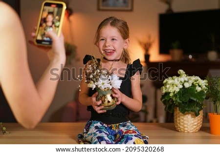 make photo child on phone with halloween pumpkin. Online call for holiday. woman is take pictures of her daughter. Take a picture with your phone. Family carving a pumpkin on Jack head. vase flowers.