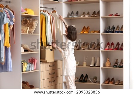 Young woman arranging clothes at wardrobe Royalty-Free Stock Photo #2095323856