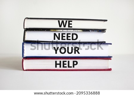 We need your help symbol. Books with concept words 'We need your help'. Businessman hand. Beautiful white background. Business, support and we need your help concept. Copy space.