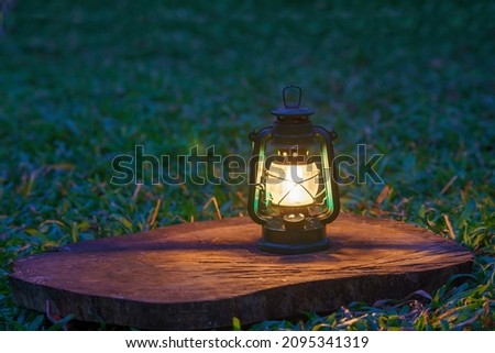 antique kerosene lamp with lights on the wooden floor in the lawn at night Royalty-Free Stock Photo #2095341319