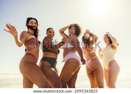 Carefree friends dancing at the beach. Happy young women smiling cheerfully while dancing in swimwear. Group of female friends having fun and enjoying their summer vacation together.