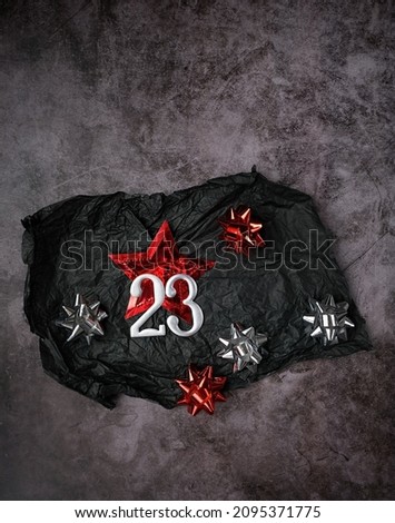 23 number, shiny star and festive bows, black wrapped paper on abstract dark background. minimal design, brutal style. top view. idea for card on 23 february holiday