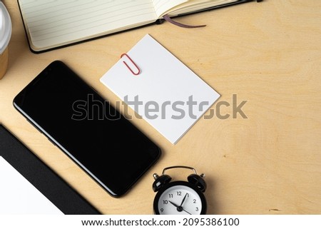 Mock up of blank business card and black smartphone screen on table