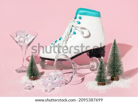 New Year creative layout with skate, martini cocktail glasses ,christmas trees, ice cubes and snow on pastel pink background. Winter creative idea. 80s or 90s retro aesthetic party celebration concept