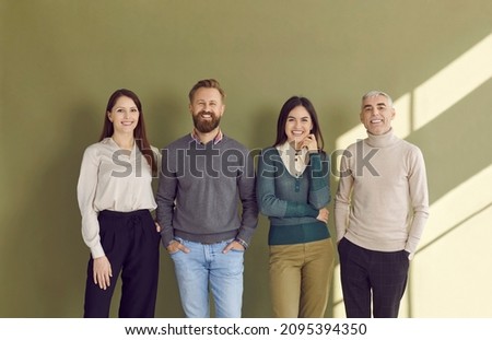 Group portrait of four happy people in smart casual outfits posing against green studio background. Team of 4 confident business men and women standing by office wall, smiling and looking at camera Royalty-Free Stock Photo #2095394350