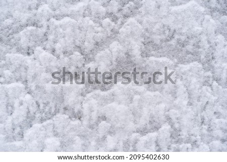texture of white snow on the wall outside in winter,
lies in waves
