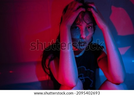Portrait in red neon light of young depressed asian woman suffering from alcohol or drug addiction, sitting in dark bathroom at home, having substance abuse problem. Depression and mental health Royalty-Free Stock Photo #2095402693