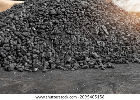 Big heap of dark black lump coal on floor bulk. Charcoal sorage at warehouse stock reserve. activated anthracite pile. Power and heat generation. Industrial and mining industry background Royalty-Free Stock Photo #2095405156