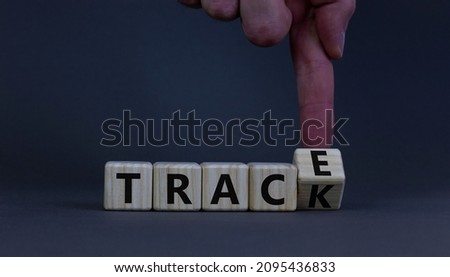 Trace and track symbol. Coronavirus Covid-19 problems. Doctor turns wooden cubes, changes the word trace to track. Beautiful grey table, grey background, copy space. Covid-19 trace and track concept.
