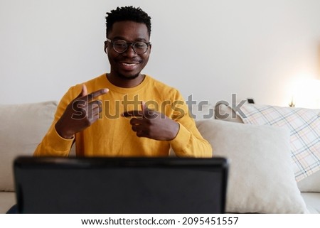 Joyful African-American man with headphones having online meeting on digital tablet at home office. African businessman wearing wireless headphones makes conference video call talk looks at pc screen.