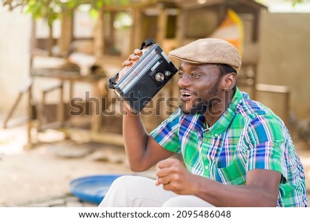 image of excited african man with a music box, black guy holding a wireless radio set- music concept Royalty-Free Stock Photo #2095486048