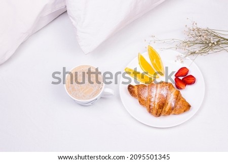 Romantic morning breakfast with croissant, strawberry and coffee in the bed.