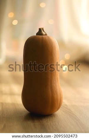 Butternut squash on wooden table, bokeh lights in the background. Selective focus.