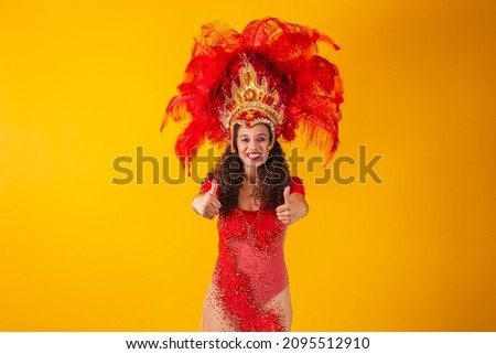 Beautiful dancer is standing with her thumb up making ok or positive sign. She is wearing a red feather costume. Carnival Fantasy